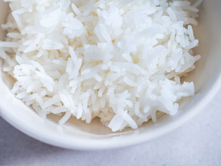 Top view of steamed rice in ceramic bowl on gray background