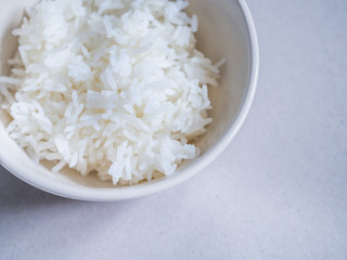 Top view of steamed rice in ceramic bowl on gray background