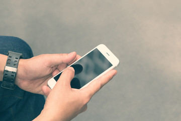 Young man using white smartphone outdoors