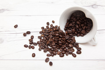 coffee beans pouring out, white ceramic tea set on wooden desk