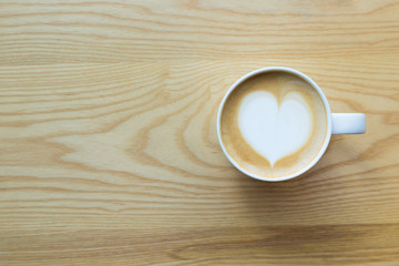 Top view of Latte coffee cup on wood table with heart shaped surface style