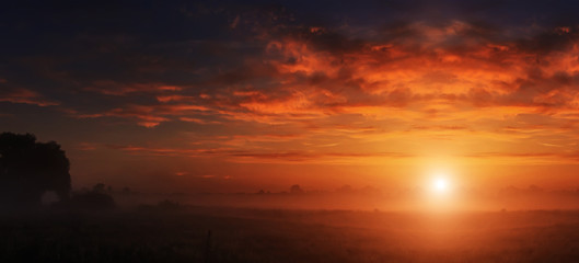 Fototapeta premium majestatyczna dramatyczna scena. fantastyczny mglisty zachód słońca nad łąką z kolorowymi chmurami na niebie. malowniczy wiejski krajobraz, mglisty poranek. kolor w naturze. piękno na świecie