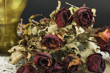 Dry roses with vase on black background