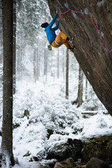 Mountain climber ascending a rock in winter snowy forest. Extrem sports. Karelian nature.
