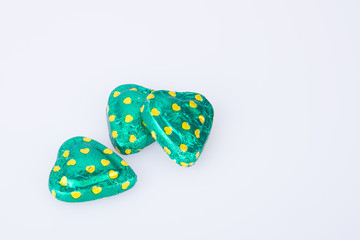 Chocolate or green foil heart-shaped chocolate on a background.