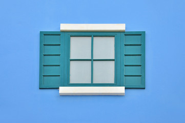 Green wooden window on blue wall