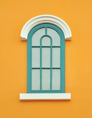 Green wooden window on yellow wall