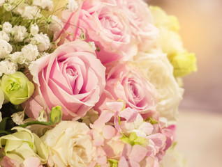 Beautiful Romantic Pink Rose Pattern in The Big Bouquet of Flowers Vase with Orange Sun Light Shade at The Corner for Interior Design, Selective Focus with Copy Space to input Text on Blur White Roses