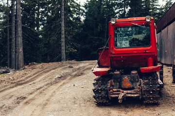 tractor bonnet and big wheels on natural soil road in spring forest