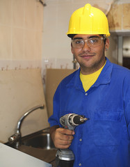 Construction worker with yellow helmet with an electric tool in hand