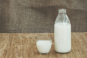 Bottle of fresh milk and one glass on wooden table