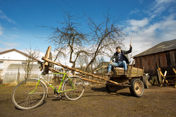 man on a cart in harness bike, village, chickens, barn