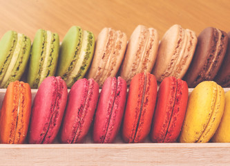 Row of traditional french colorful macarons in box, vintage toned