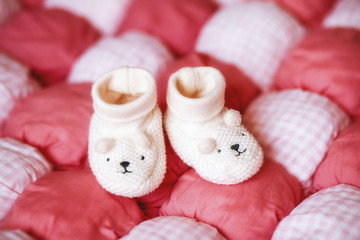 Fototapeta na wymiar Cute white baby booties on red blanket. Pregnancy concept