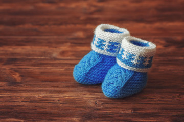 Blue crochet baby booties on wooden background, copyspace, vintage toned