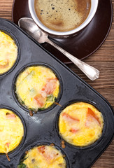 Breakfast egg muffins with ham, cheese and vegetables. Cup of coffe.