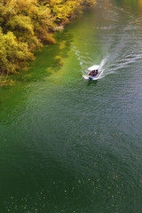 Beautiful landscape view with boat on the river and colorful autumn forest