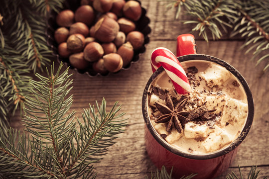 Hot chocolate with marshmallows on the wooden background fir-tree. Christmas tree with candy cane and mug with coffee. New Year. Vintage and toned image. Rustic style. Close up.