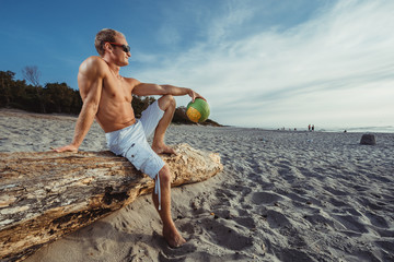 slender man in shorts with a volley ball on the beach, white sand