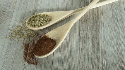 crossed wood spoons on wood table with spices on them