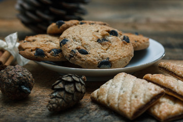 Chocolate chip cookies on rustic background. Nearby lie cinnamon sticks and cones.