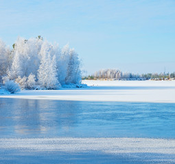 Winter landscape with frozen river and forest in the frost