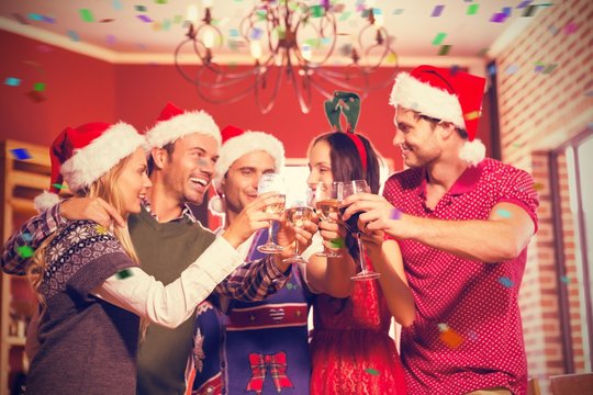 Composite image of cute group of friends toasting with santa hat