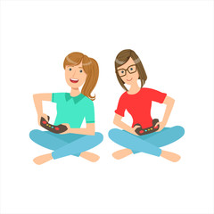 Two Teenage Girlfriends Sitting With Legs Crossed Playing Video Games With Controllers, Part Of Women Different Lifestyles Collection