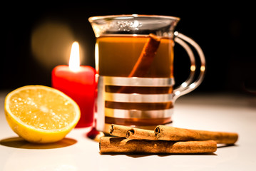 Weihnachtlicher Tee mit Zitrone, Zimt und Kerze