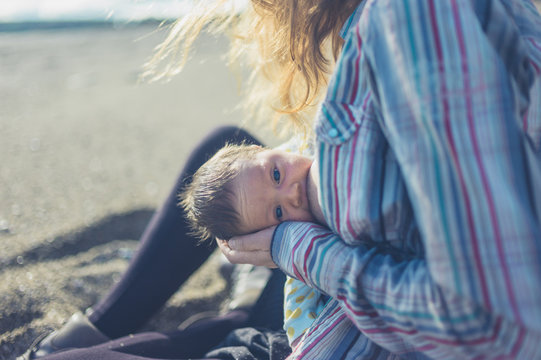 Mother breastfeeding baby on beach