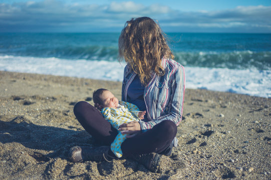 Mother sitting on beach with baby