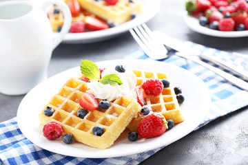 Homemade waffles with berries in plate on grey table