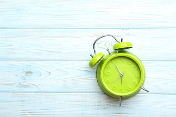 Green alarm clock on a blue wooden table