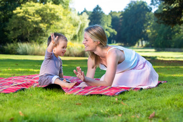 Little boy waving hand up with mother at park.