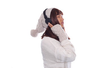 Attraktive junge Frau mit Wintermütze und schwarzen Kopfhörern hört Musik
