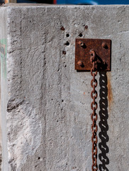 Old rusty heavy chain hanging along the wall