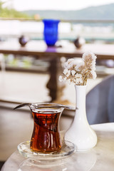 Turkish tea with authentic glass cup and decorative vase with flowers