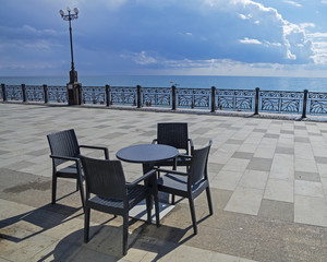 A table and four chairs on an empty seafront.  Crimea.