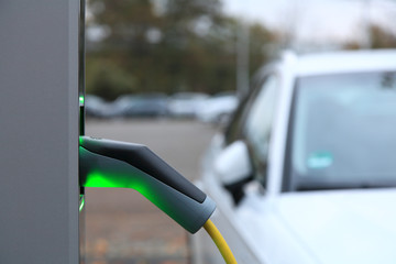 View from an Electric Car Charging Column and in the background a partial view of a white car 