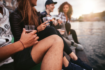 Group of people sitting on pier and having drinks