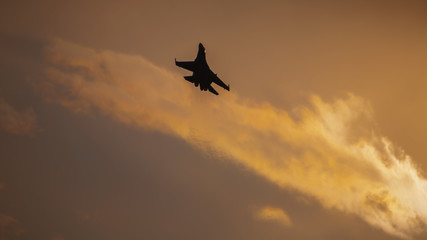 Military jet flying at sunset