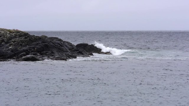 Waves splash against the coastline rocks on a foggy day. Atlantic Ocean.