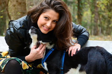 beautiful young woman sitting in the autumn park with her border collie dog