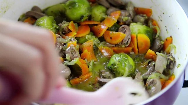 Process of cooking chicken hearts with Brussels sprouts- mixing the ingredients in the pan