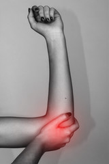 Elbow pain. Beautiful female holding her elbow. Pain concept close-up  over gray background  black...