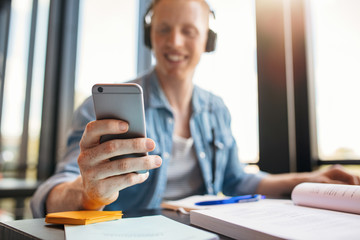 Male student in library using mobile phone