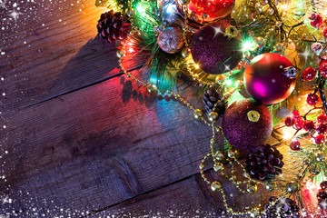 Christmas and new year background. Tree fir snow, shining garlands, balls and decor on wooden table. Top view with copy space. 