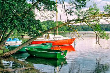 Łódki i żaglówka przy brzegu jeziora - obrazy, fototapety, plakaty