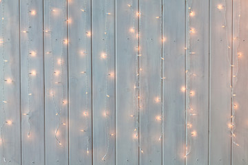 Christmas lights burning on a white wooden background. New Year back.