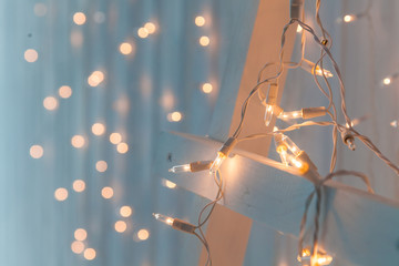 Fototapeta na wymiar Christmas lights burning on a white wooden background. New Year back.